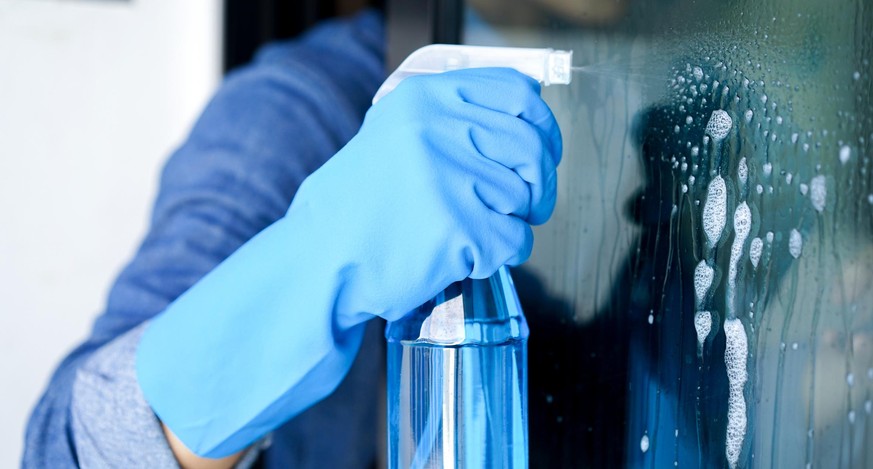 close up male housekeeper hand using spray bottle for cleaning dust on mirror door concept
