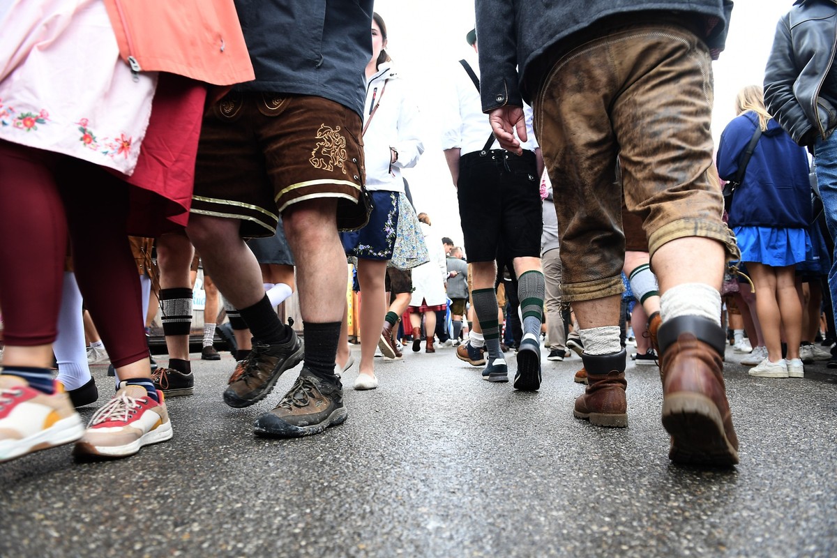 28.09.2024, Bayern, München: Zünftig gekleidet, in Lederhosen und Dirndln, gehen Gäste an dem regnerischen Tag über die Wiesn. Das 189. Oktoberfest findet vom 21. September bis 6. Oktober 2024 auf der ...