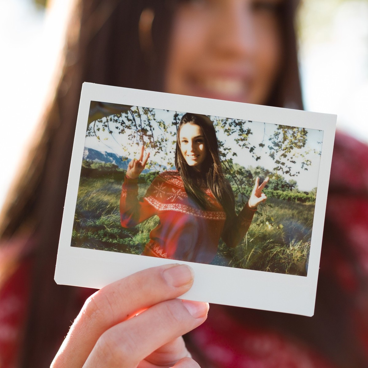 Young woman holding an instant photo print where she is happy