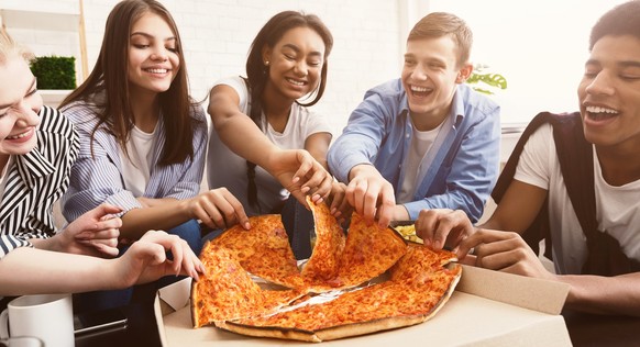 Time for snack. Happy students eating pizza and chatting at home