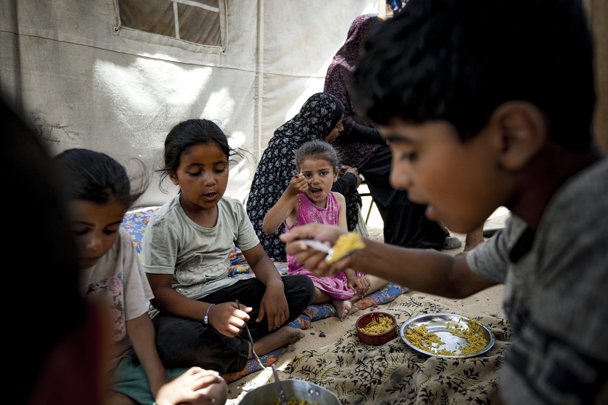 Members of the Al-Ashqar family, who were displaced by the Israeli bombardment of the Gaza Strip, eat lunch at a makeshift tent camp in Khan Younis, southern Gaza Strip, Thursday, July 4, 2024. Over n ...