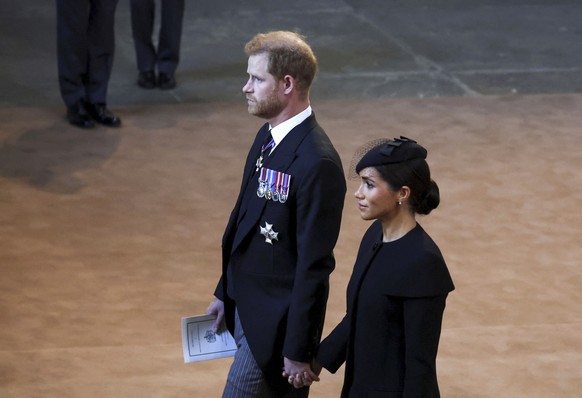 Britain's Prince Harry and Meghan, Duchess of Sussex, walk inside Westminster Hall in London, Wednesday, Sept. 14, 2022. The Queen will lie in state in Westminster Hall for four full days before her f ...