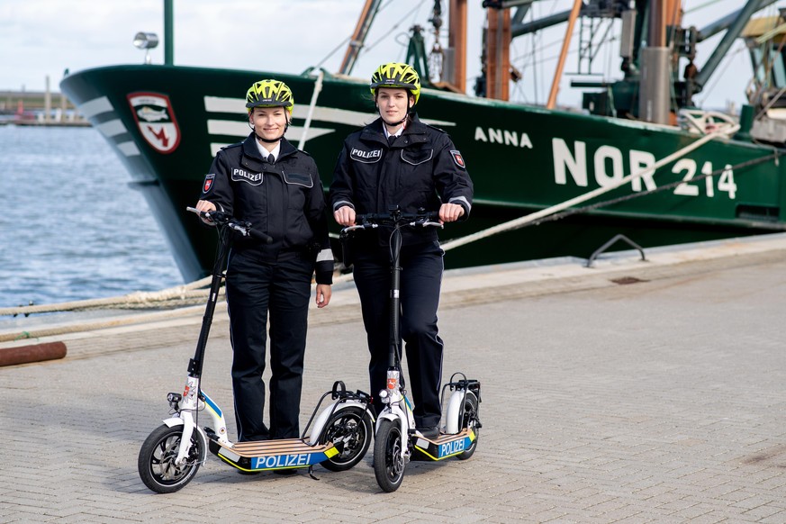 30.03.2022, Niedersachsen, Norddeich: Franziska Schrader (l), Streifenbeamtin in Aurich, und Constanze von Garrel, Streifenbeamtin in Wittmund, stehen während eines Pressetermins mit den neuen E-Scoot ...