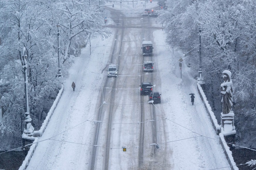 02.12.2023, Bayern, München: Passanten und Pkw bahnen sich ihren Weg über die Maximiliansbrücke. Schnee und Eis haben im Süden Bayerns auf den Straßen und bei der Bahn für Chaos gesorgt. Foto: Peter K ...