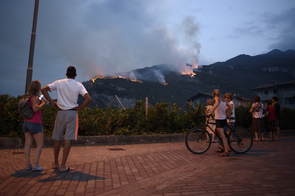 11.07.2022, Italien, Nago: Einheimische beobachten, wie das Feuer am zweiten Tag der Br�nde in Nago, Italien, die Vegetation vernichtet. Seit dem Ausbruch eines Feuers am 10. Juli 2022 in Nago, einer  ...