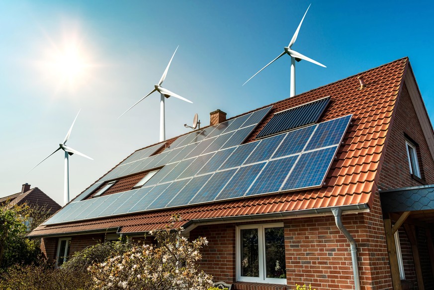 Solar panel on a roof of a house and wind turbins arround - concept of sustainable resources