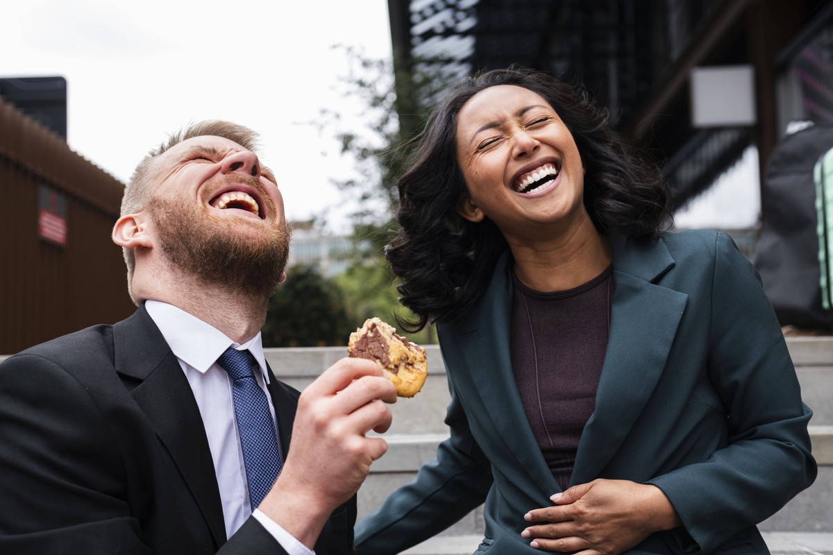 Cheerful businesswoman with businessman holding cookie near buildings model released, Symbolfoto, AMWF02973