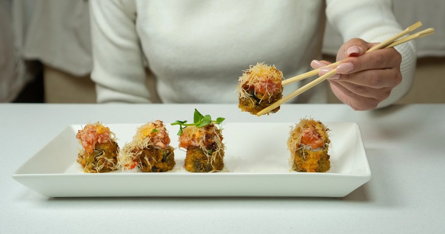 Girl eats sushi and california roll using hashi