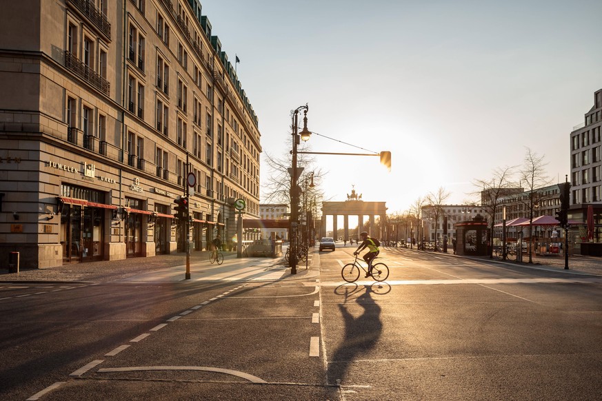 Corona Berlin Radfahrer vor dem Hotel Adlon, hinten das Brandenburger Tor, Social Distancing, Sonnenuntergang Berlin, 08.04.2020 Berlin Berlin Deutschland *** Corona Berlin cyclists in front of the Ho ...