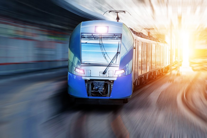 Passenger train passes station in urban landscape