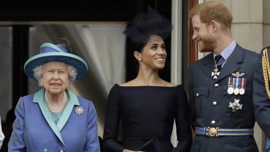 FILE - In this Tuesday, July 10, 2018 file photo Britain's Queen Elizabeth II, and Meghan the Duchess of Sussex and Prince Harry watch a flypast of Royal Air Force aircraft pass over Buckingham Palace ...