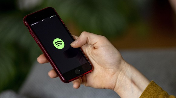 Auf dem Bildschirm eines Smartphones sieht man das Logo der App Spotify.