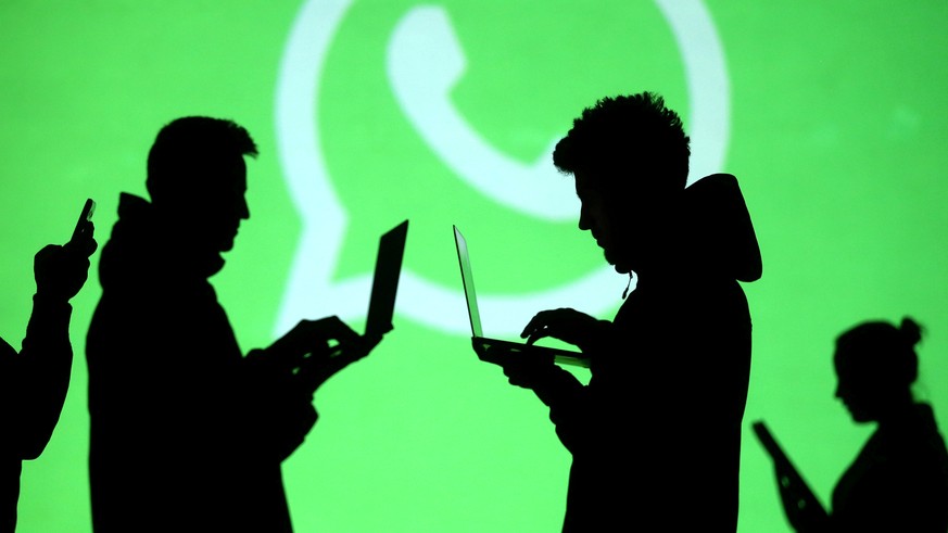 FILE PHOTO: Silhouettes of laptop and mobile device users are seen next to a screen projection of Whatsapp logo in this picture illustration taken March 28, 2018. REUTERS/Dado Ruvic/File Photo