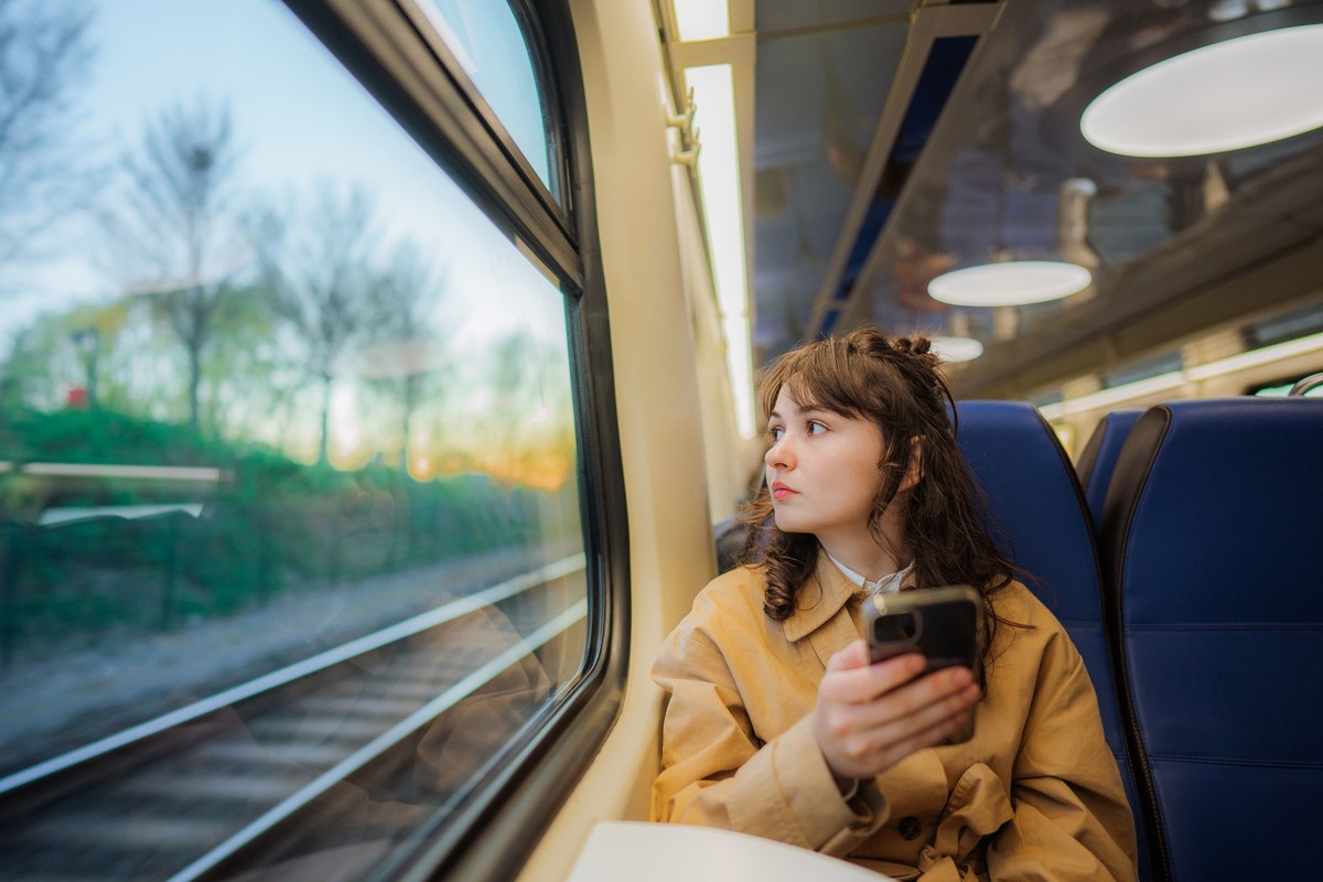 Young Caucasian woman using smartphone while traveling in the train