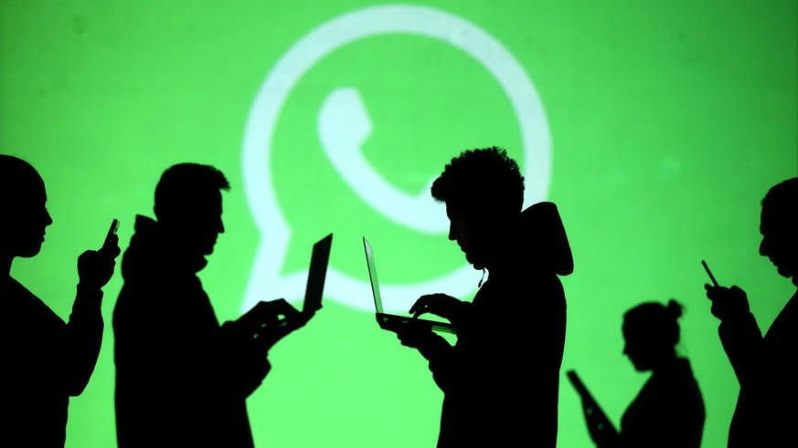 FILE PHOTO: Silhouettes of laptop and mobile device users are seen next to a screen projection of Whatsapp logo in this picture illustration taken March 28, 2018. REUTERS/Dado Ruvic/File Photo