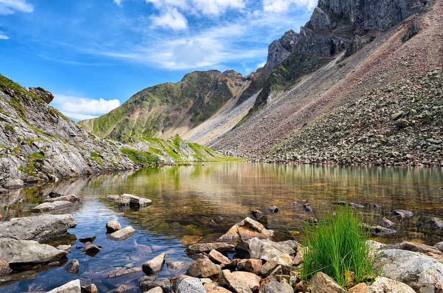 Little shallow lake with clear clear water in Siberian mountains. High mountain tundra. Eastern Siberia. Russia