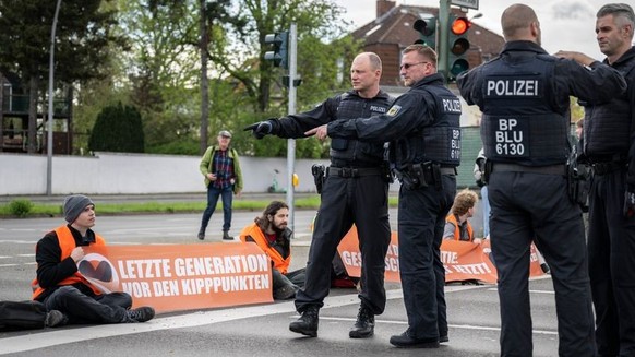 24.04.2023, Berlin: Polizisten besprechen die Vorgehensweise zur Räumung der Kreuzung Hohenzollerndamm/Konstanzer Straße, wo Aktivisten auf der Fahrbahn sitzen. Am Montag will die Letzte Generation na ...