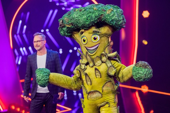 01.10.2022, Nordrhein-Westfalen, K�ln: Die Figur &quot;Der Brokkoli&quot; steht in der Prosieben-Show &quot;The Masked Singer&quot; auf der B�hne neben Moderator Matthias Opdenh�vel. Foto: Rolf Vennen ...