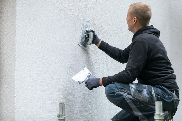 construction worker putting decorative plaster on house exterior