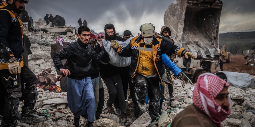 06.02.2023, Syrien, Harem: Zivilisten und Mitglieder des syrischen Zivilschutzes führen Such- und Rettungsmaßnahmesuchen in den Trümmern eines zerstörten Gebäudes durch. In der Türkei und in Syrien si ...
