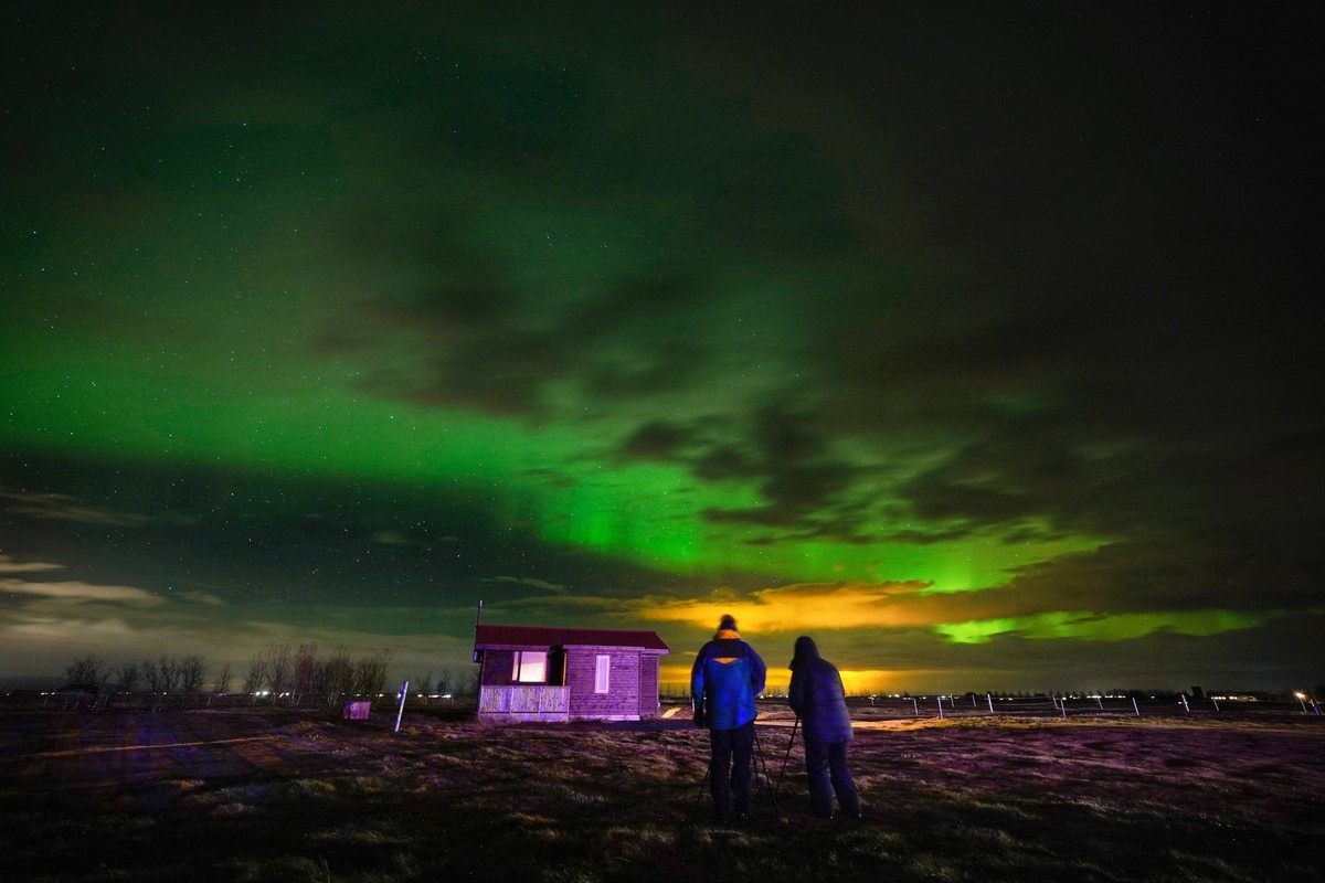 dpatopbilder - 24.11.2022, Island, Arabaer: Menschen beobachten die Nordlichter auf einem Bauernhof in Arabaer bei Selfoss in Island. Foto: Owen Humphreys/PA Wire/dpa +++ dpa-Bildfunk +++