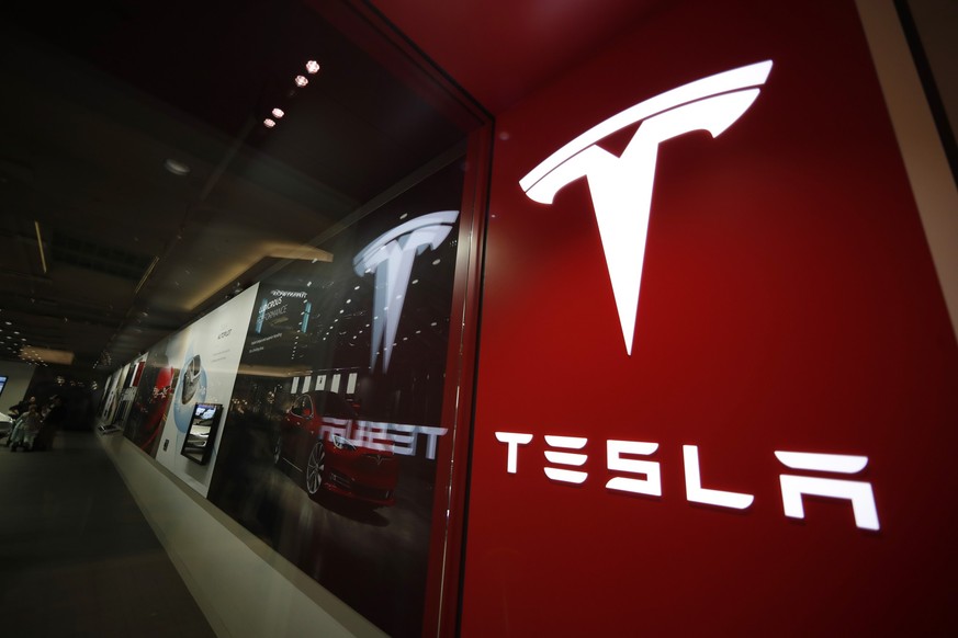 FILE - A sign bearing the Tesla company logo is displayed outside a Tesla store in Cherry Creek Mall in Denver, Colorado, Feb. 9, 2019. U.S. safety regulators are turning up the heat on Tesla, announc ...