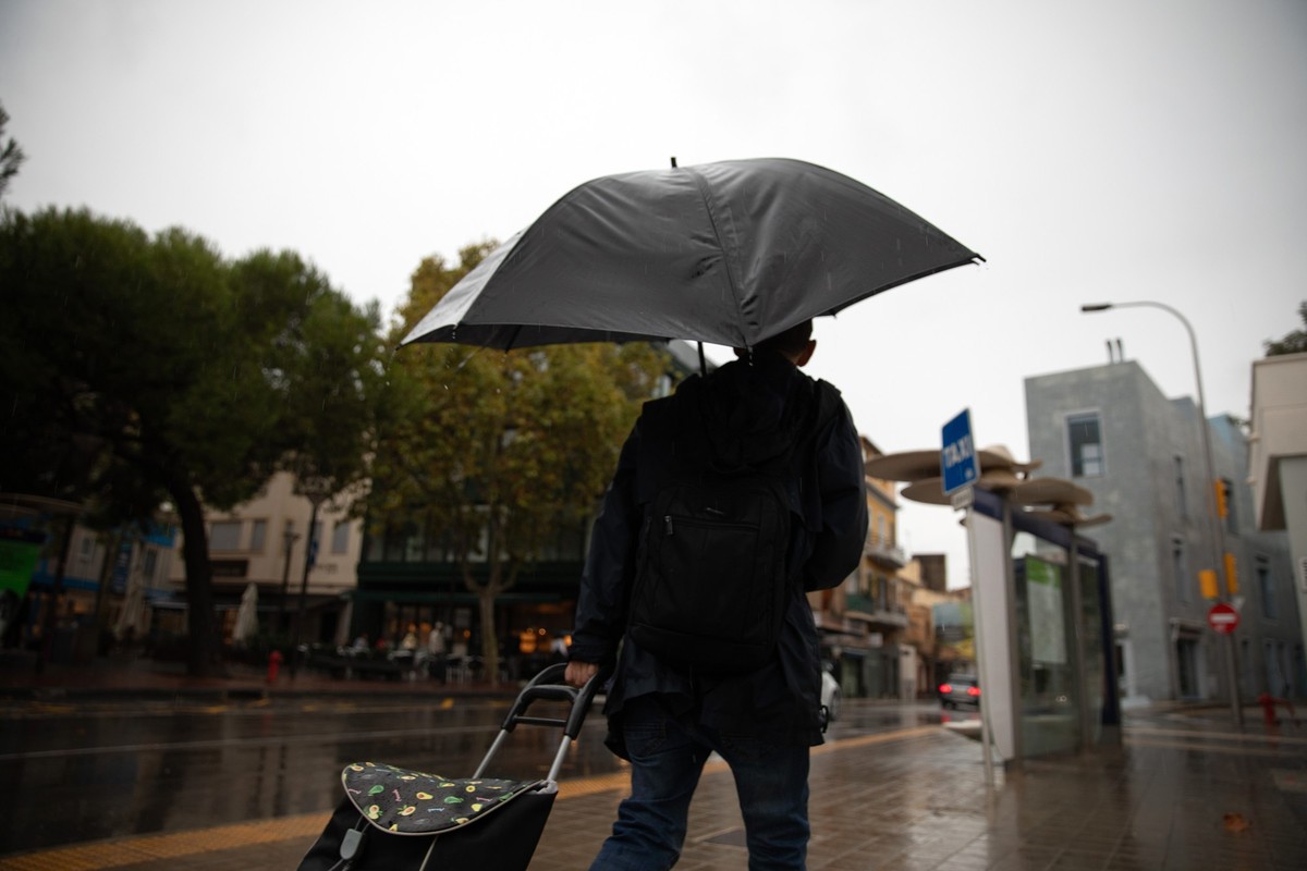 26.10.2024, Spanien, Palma de Mallorca: Ein Mann geht an einem regnerischen Tag mit einem Regenschirm in der Inselhauptstadt spazieren. Regen und Stürme lassen auf Mallorca die Temperaturen sinken. Fo ...