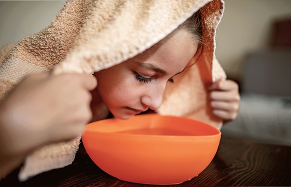 Aromatherapy. Little girl making inhalation with steamed aromatic water from the bowl