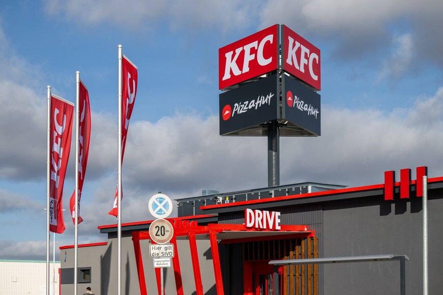 Fast-Food-Ketten KFC und Pizza Hut , Food, Deutschland, Baden-Württemberg, Hockenheim, 05.02.2024, KFC und Pizza Hut Werbetafeln mit Fahnen gegen Himmel. *** Fast food chains KFC and Pizza Hut , Food, ...