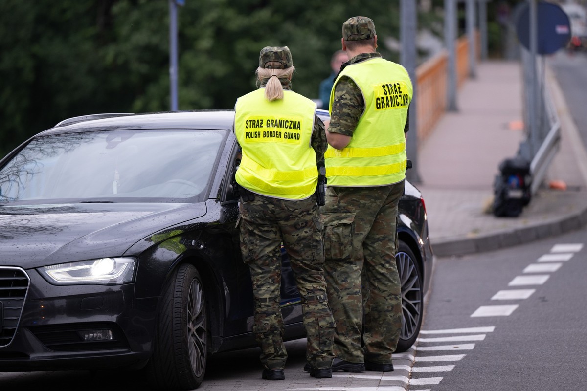 07.07.2025, Polen, Zgorzelec: Polnische Grenzschützer stehen auf der polnischen Seite hinter der Stadtbrücke von Görlitz und kontrollieren ein Fahrzeug. Polen hat vorübergehend die Grenzkontrollen an ...