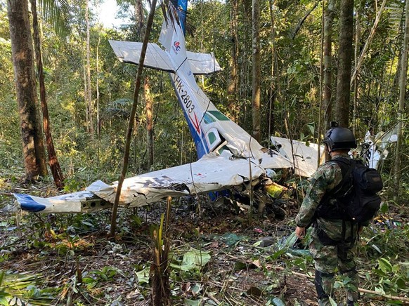 HANDOUT - 18.05.2023, Kolumbien, -: Auf diesem von der Pressestelle der kolumbianischen Streitkräfte veröffentlichten Bild steht ein Soldat vor dem Wrack einer Cessna C206, die im Dschungel von Solano ...