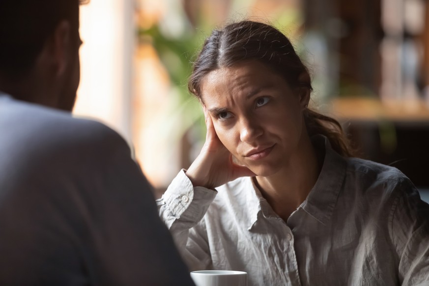 Focus on mixed race irritated young female sitting in cafeteria on speed dating with boring male rear view. Unsuccessful unlucky romantic date failure, bad first impression and poor companion concept