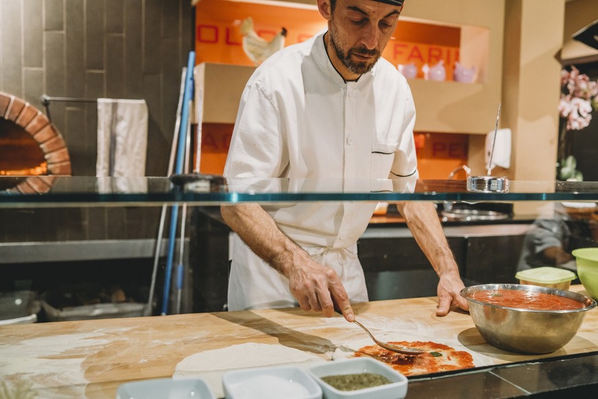 Pizza chef preparing a pizza at the restaurant