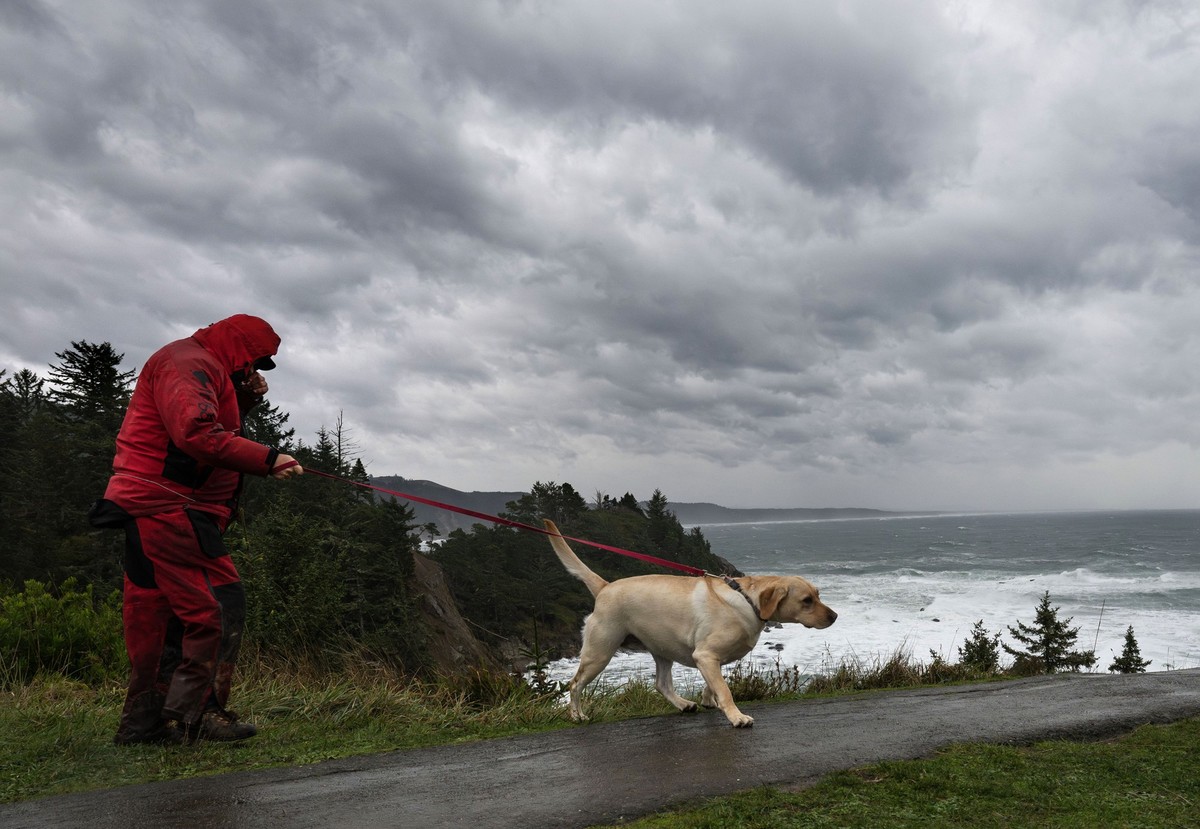 dpatopbilder - 19.11.2024, USA, Cape Arago: Brian Royce spaziert mit seinem Hund Blue auf einer Klippe mit Blick auf den Pazifischen Ozean am Cape Arago im Südwesten von Oregon, während ein gewaltiger ...