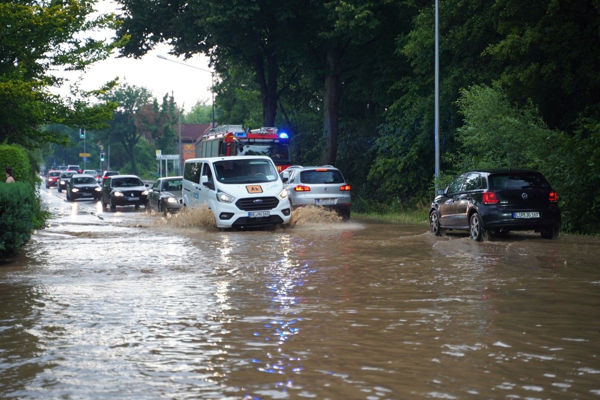 27.06.2024, Nordrhein-Westfalen, Detmold: Autos fahren nach einem Unwetter durch Wasser, das auf einer �berfluteten Stra�e steht. Bei einem heftigem Unwetter in Detmold im Kreis Lippe sind nach Stadta ...