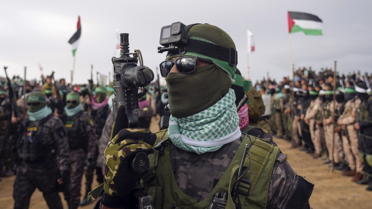 20.02.2025, Palästinensische Gebiete, Chan Junis: Vermummte und bewaffnete Kämpfer der Terrororganisation Hamas gehen in Stellung, bevor sie die Leichen von vier israelischen Geiseln, darunter eine Mu ...