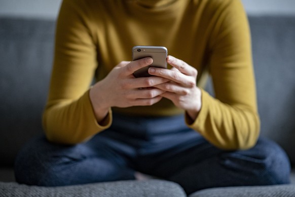 ARCHIV - 24.04.2021, Berlin: Eine junge Frau h�lt ein Smartphone in der Hand. Forscher weisen auf einen Zusammenhang zwischen dem Nachrichtenkonsum und der Gesundheit hin. (zu dpa �Studie: Zusammenhan ...