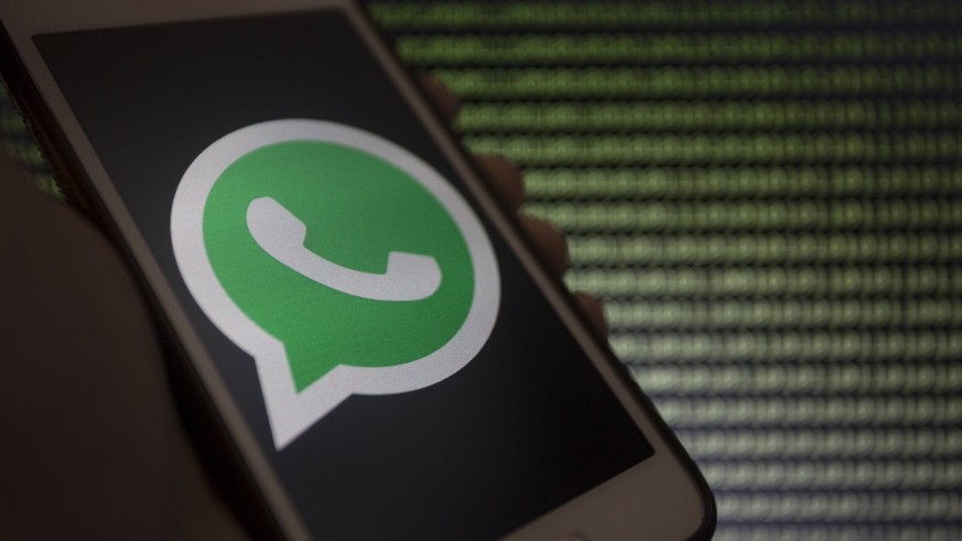 May 14, 2019 - Asuncion, Paraguay - Hand holds a smartphone displaying WhatsApp logo icon against binary code text unfocused on background. Asuncion Paraguay PUBLICATIONxINxGERxSUIxAUTxONLY - ZUMAc217 ...