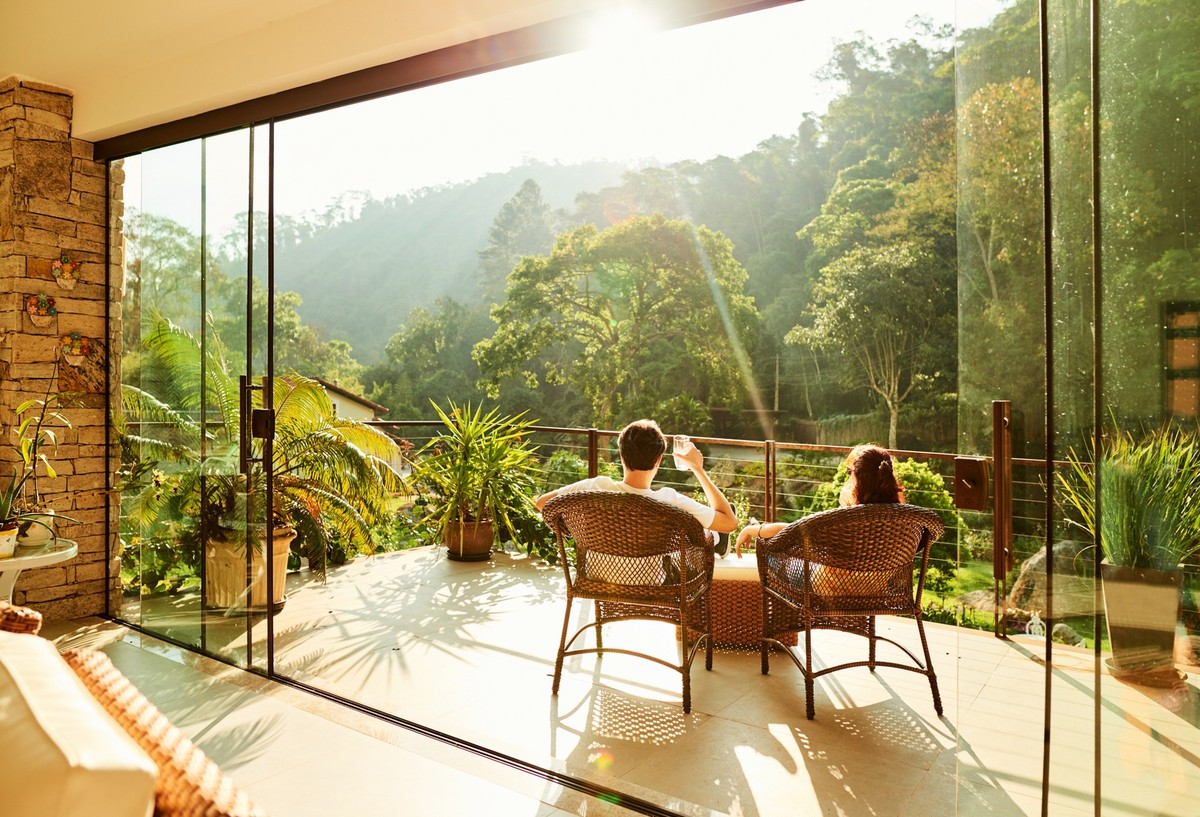 Rear view of a couple relaxing in the chairs at hotel balcony