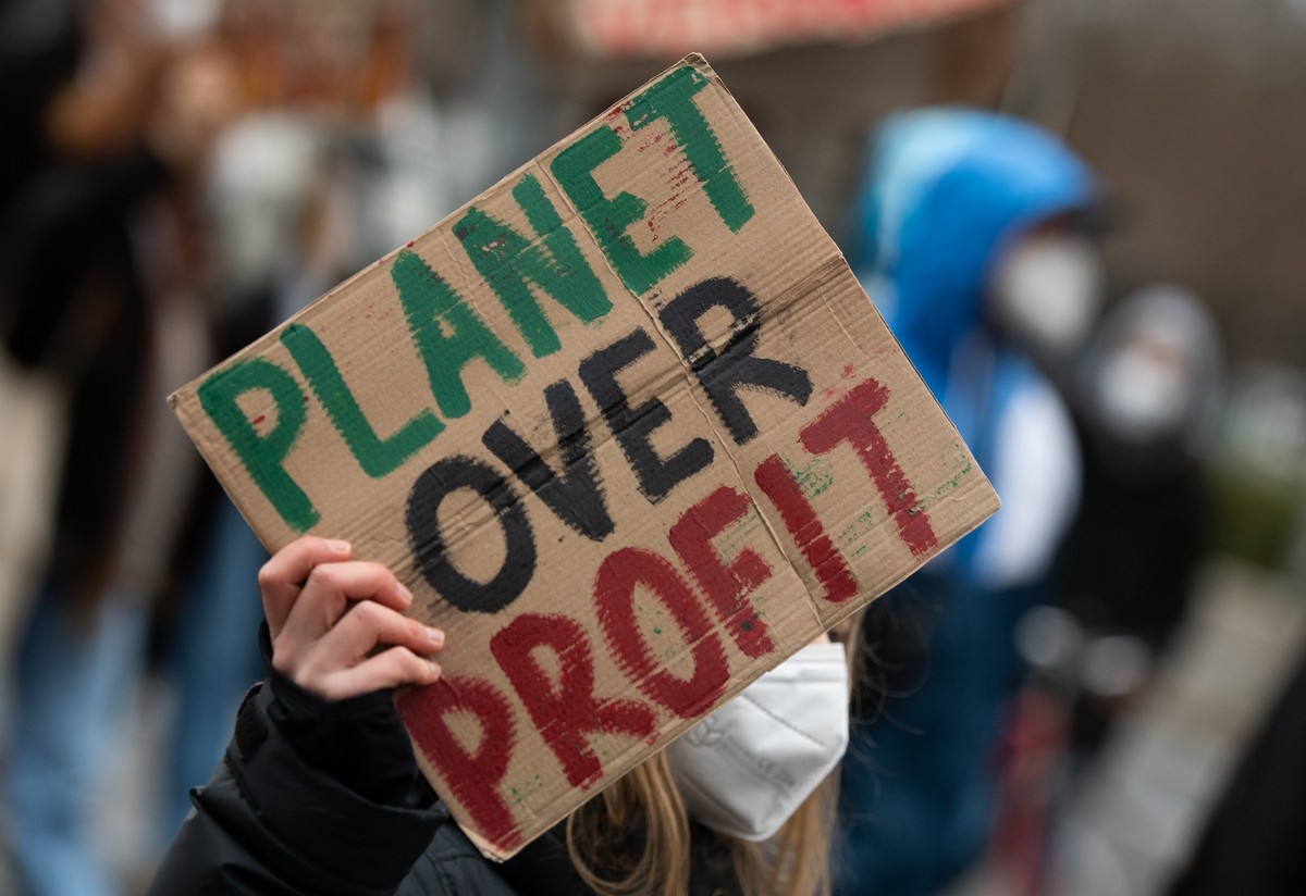 ARCHIV - 17.12.2021, Berlin: Bei einer Demonstration der Klimaaktivisten Fridays For Future trägt eine Teilnehmerin ein Plakat mit der Aufschrift "Planet over Profit". In keinem einzigen der ...