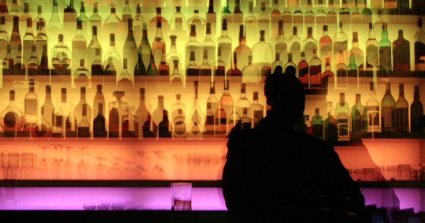 ARCHIV - 19.12.2006, Hessen, Frankfurt\Main: Ein Mann sitzt in einer Kneipe in Frankfurt am Main vor einem bunt beleuchtetem Regal an der Bar (Foto mit Zoomeffekt). In der Silvesternacht wird viel gef ...