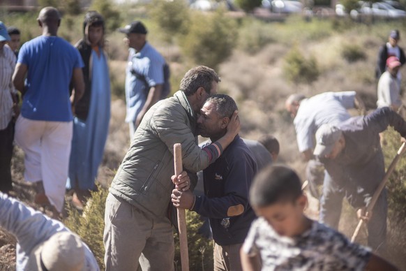09.09.2023, Marokko, Marrakesch: Menschen trösten sich gegenseitig, während sie Gräber für die Opfer des Erdbebens im Dorf Ouargane in der Nähe von Marrakeschm ausheben. Ein starkes Erdbeben hat am Fr ...