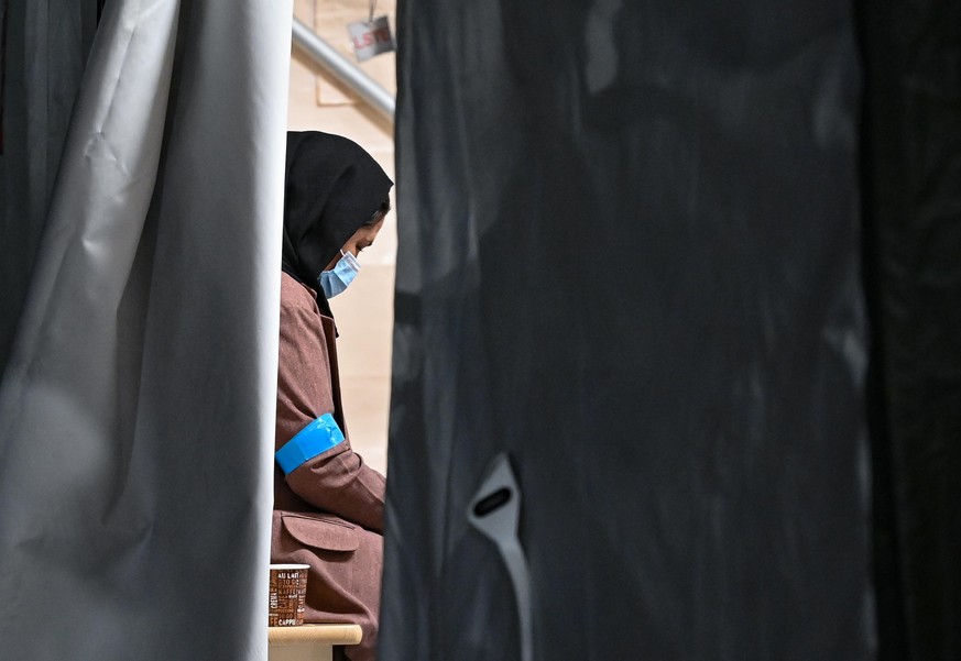 Eine Frau, die zusammen mit weiteren Ortskräften aus Afghanistan am frühen Morgen auf dem Gelände der DRK-Flüchtlingshilfe in der Erstaufnahmeeinrichtung angekommen ist, sitzt in einem Zelt. Gegen 4:3 ...