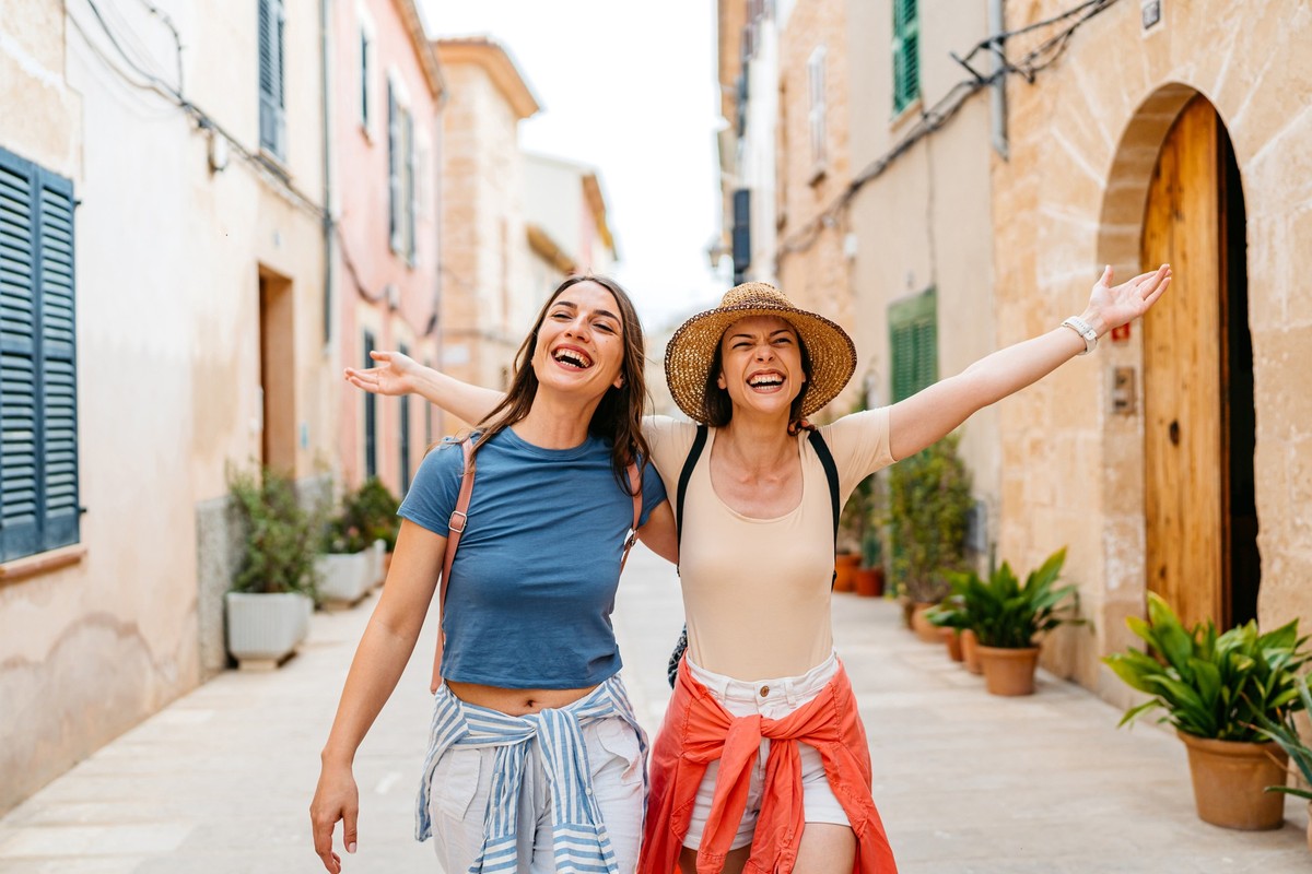 Two female friends having fun while walking on the street in Alcúdia in Mallorca in Spain.