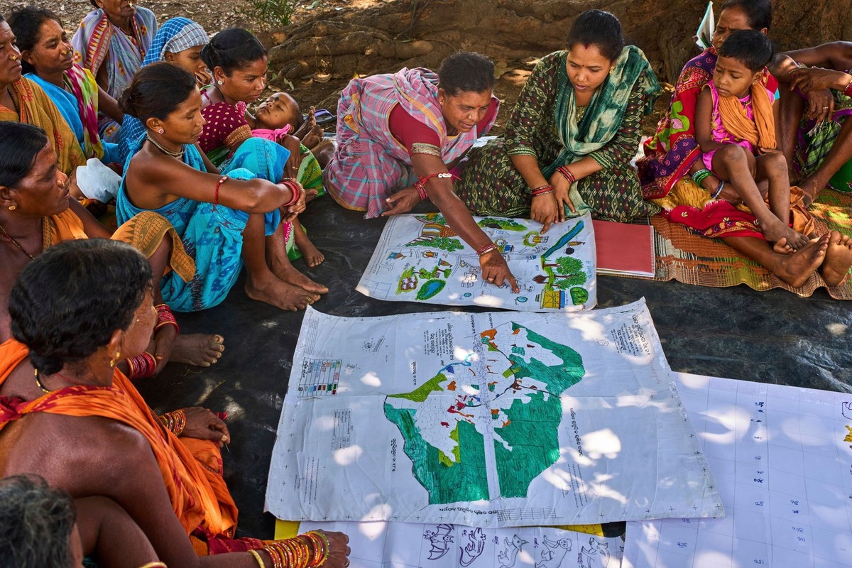 Kamala Kadria, third from right, a woman from the Gadaba Indigenous community, points to a spot on a map they made as others look on in Hatipakna village, Koraput district, in India's eastern sta ...