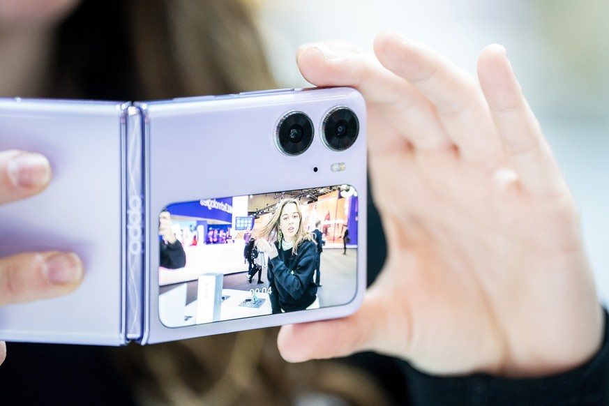 01.03.2023, Spanien, Barcelona: Oppo-Mitarbeiter testen die Kamera des Smartphones Oppo Find N2 Flip während des Mobile World Congress 2023 in Barcelona. Die viertägige Messe ist das weltweit größte u ...