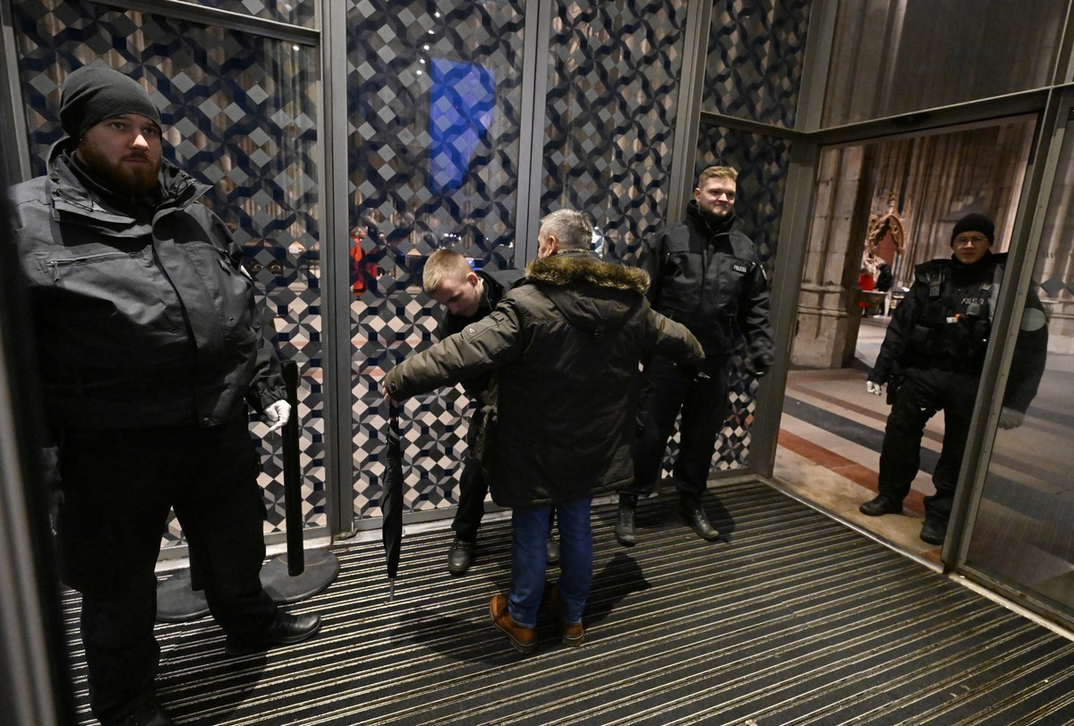 24.12.2023, Nordrhein-Westfalen, Köln: Polizisten kontrollieren am Eingang des Kölner Doms jeden Besucher der Frühmesse am Weihnachtstag. Aufgrund von Hinweisen auf einen geplanten islamistischen Ansc ...