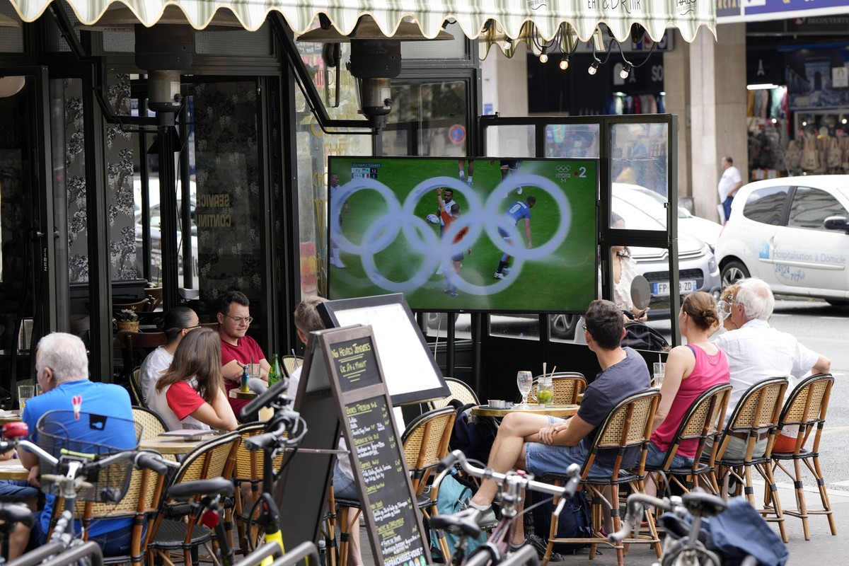 People watch a rugby match between France and Fiji at a street cafe during the 2024 Summer Olympics, Thursday, July 25, 2024, in Paris, France. (AP Photo/Martin Meissner)