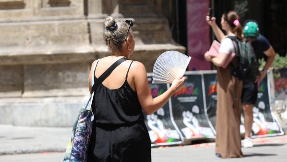 16.07.2023, Italien, Palermo: Eine Frau benutzt ihren Fächer während der Hitze. Temperaturen um die 40 Grad tagsüber und 30 Grad nachts machen den Menschen in weiten Teilen Südeuropas zu schaffen. Fot ...