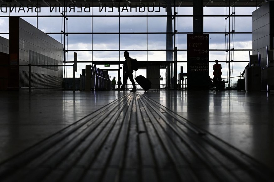 A passenger walks through the fairly empty main terminal of the BER Berlin Brandenburg airport as departing flights were cancelled due to a strike by security workers on April 24, 2023 in Schoenefeld  ...
